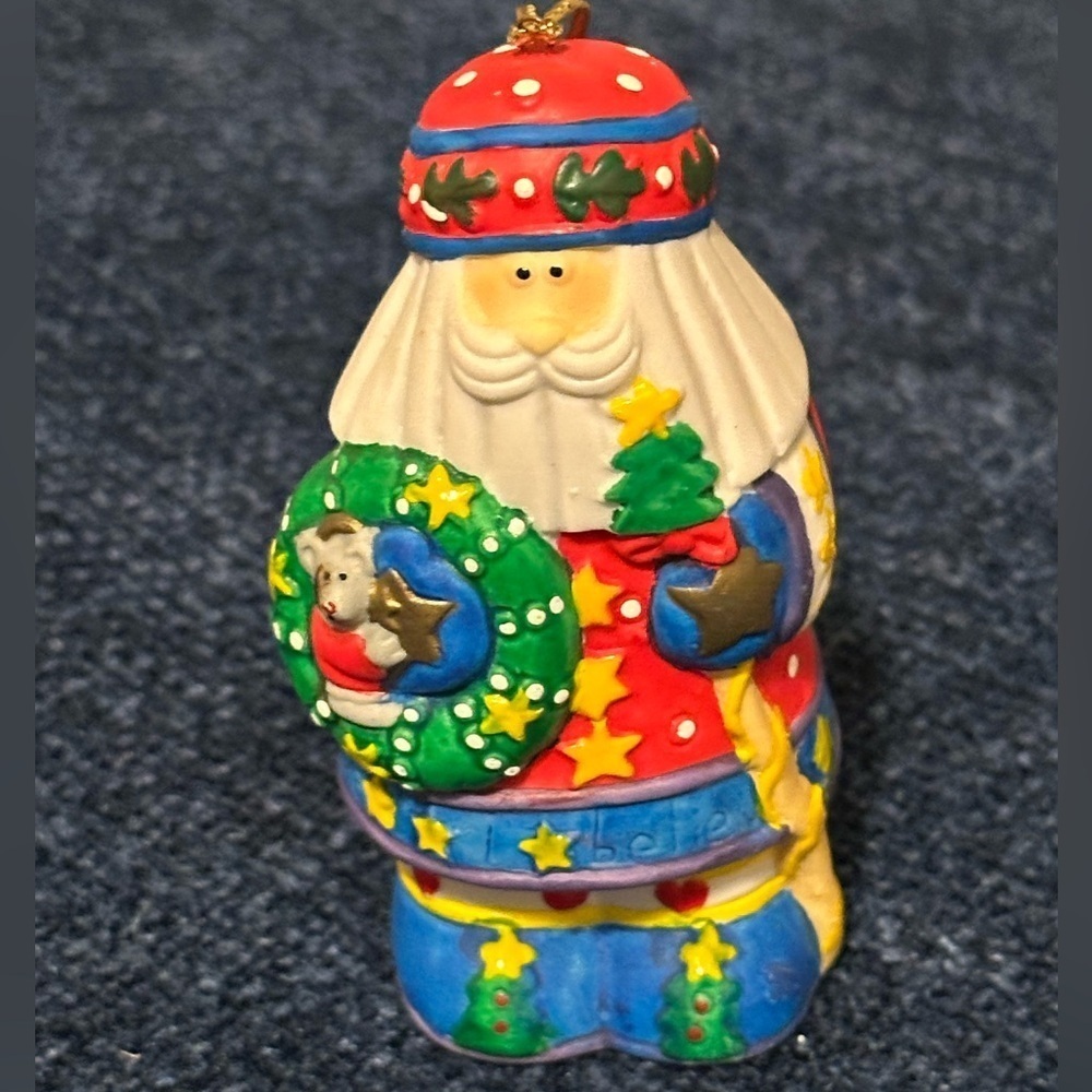 Brightly colored ceramic Santa ornament. Santa carries a tree & wreath.